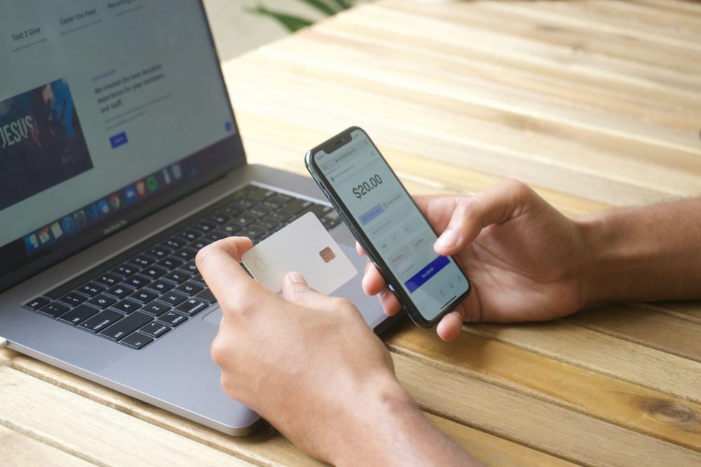 A person paying online with a phone and a laptop